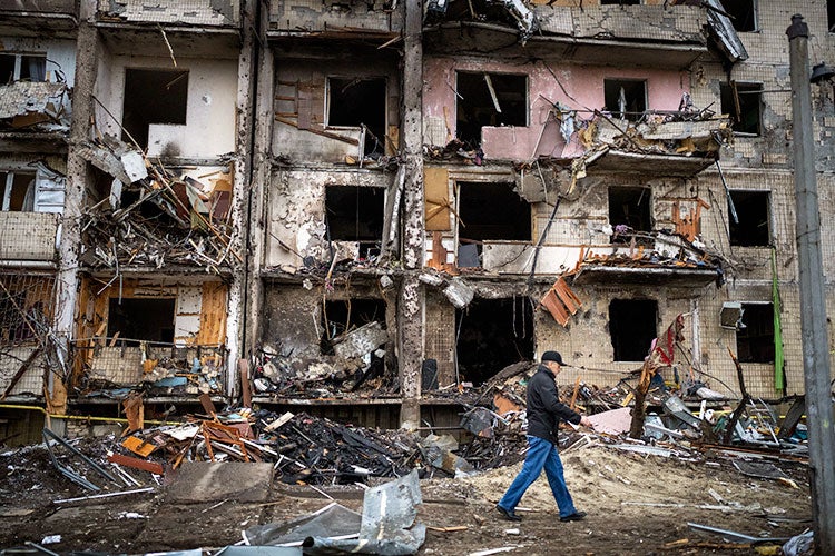 Man walking by a bombed out building
