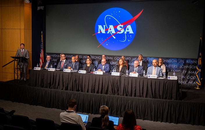 A panel of people at a NASA conference viewed from a distance