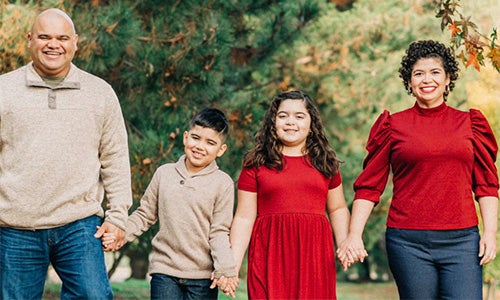 Two parents and two children smiling and holding hands