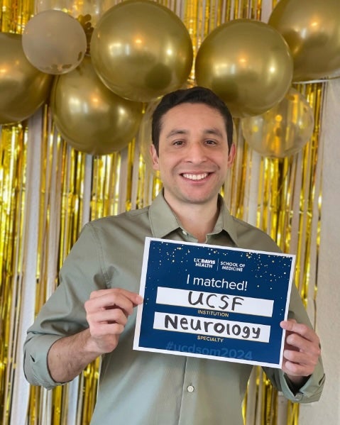 Javier Rodriguez holds a sign reading "I Matched! UCSF Neurology"