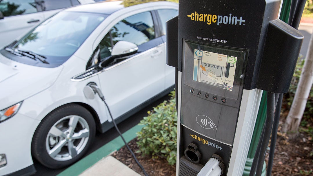 An electric vehicle parked on the street connected to a charging station