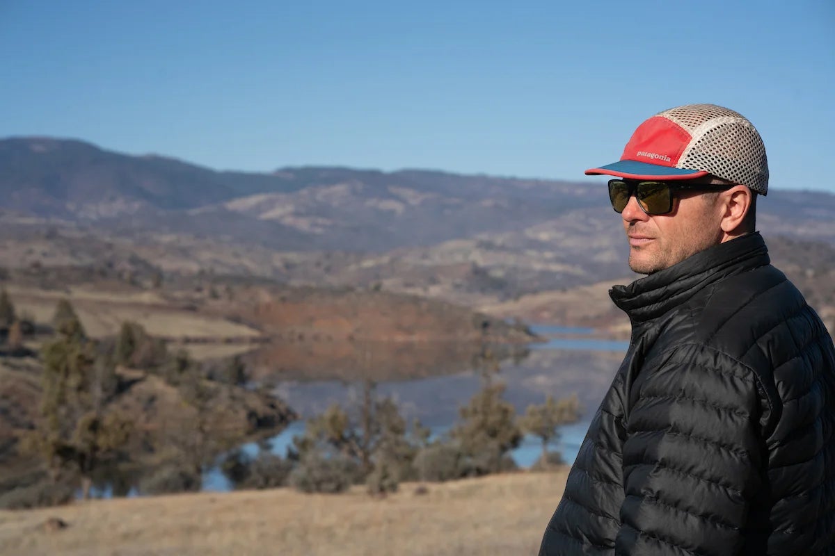 A man standing in front of a landscape of mountains and river