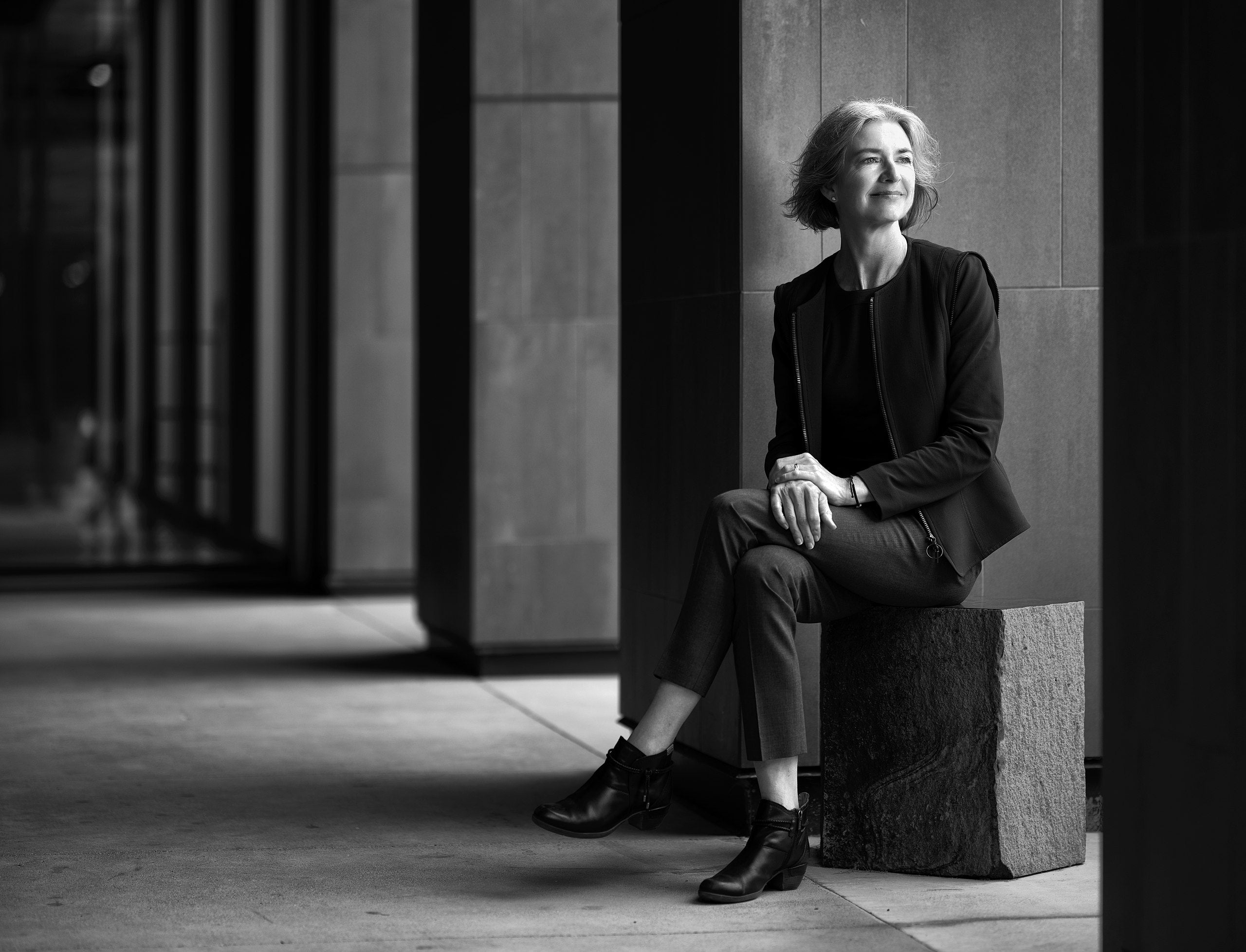 A woman sitting inside a colonnade looking into the distance