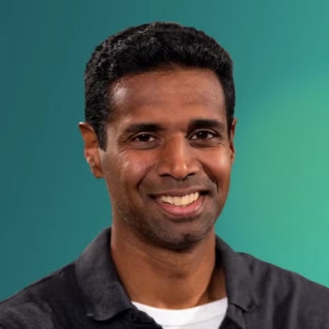 Chetan Nayak smiles at the camera against a gradient teal blue background.