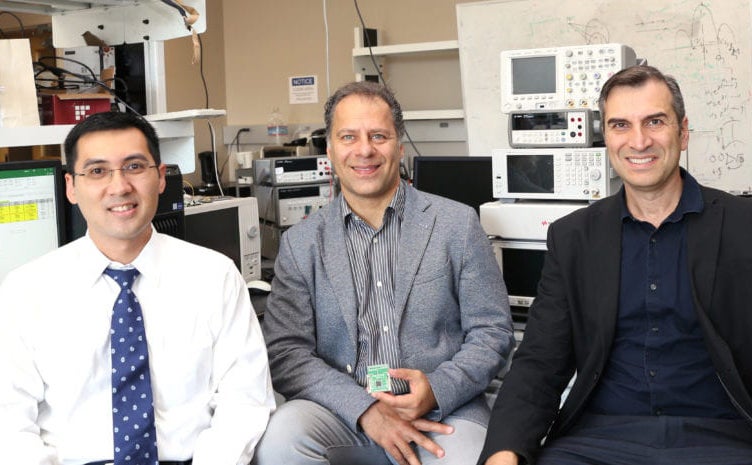 Three men sitting in a lab 