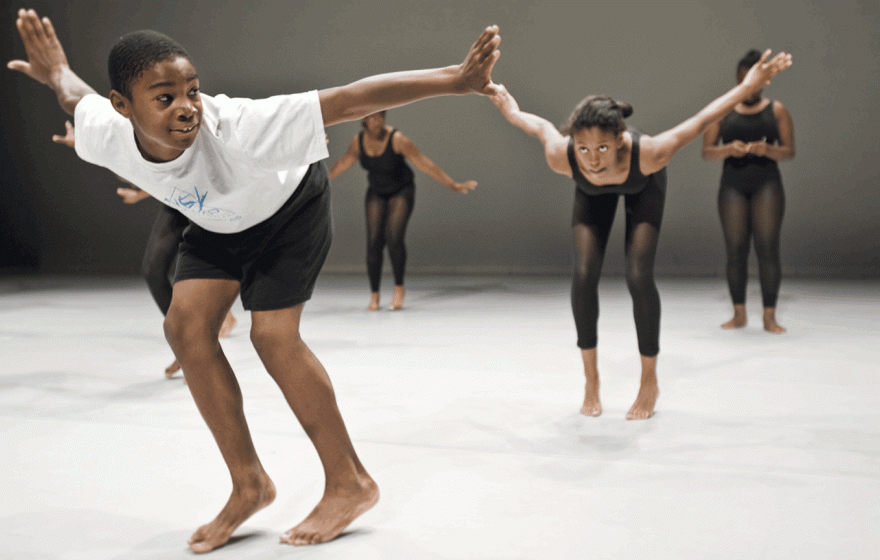 Camilo Eifler and three other dancers on stage, leaning forward dynamically with their arms outstretched