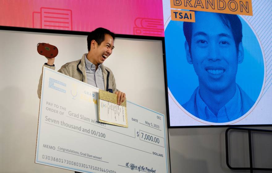 Brandon Tsai holds up the trophy, the Slammy, and his winning check at UC Grad Slam 2023