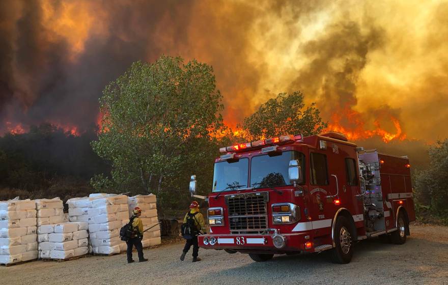 Fire truck and two firefighters with Chaparral fire behind