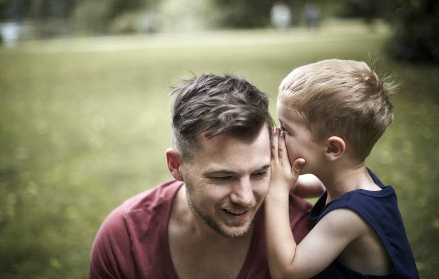 Child whispering in father's ear