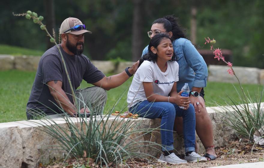 A girl cries outside the Willie de Leon Civic Center in Uvalde, Texas, on May 24, 2022, surrounded by two adults