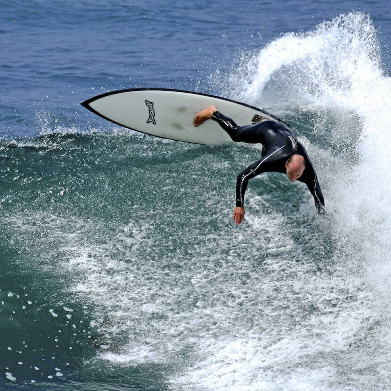 Tyler Callaway in a wetsuit, aggressively surfing a 10-foot wave